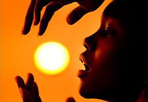 A sun between the hands and face of a person